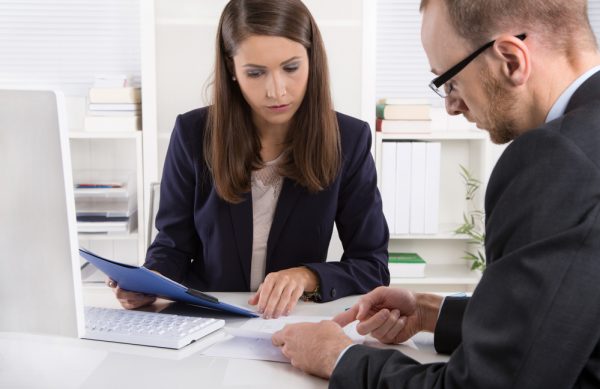 Customer and smiling female financial agent in a discussion at desk.
