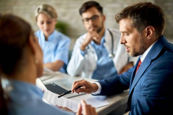 Mid adult businessman and healthcare workers analyzing documents during a meeting in the office.